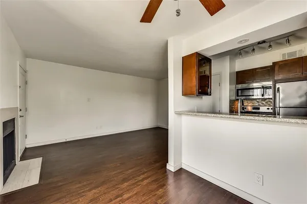 a view of kitchen with stainless steel appliances wooden floor and empty shelves