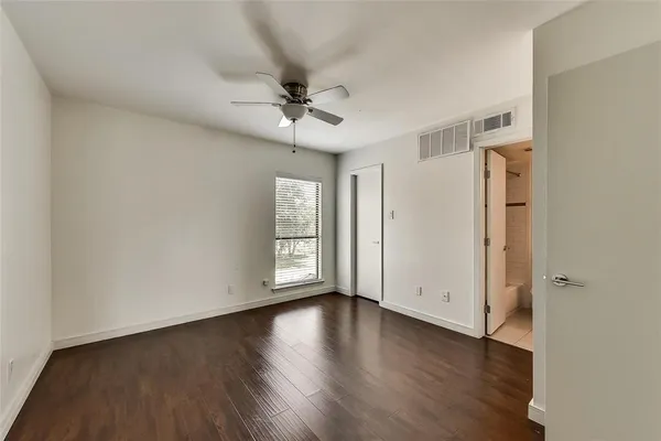 an empty room with wooden floor chandelier fan and windows