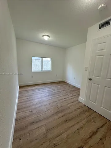 an empty room with wooden floor and white walls