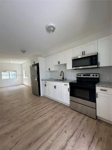 a kitchen with granite countertop a stove a sink and a refrigerator