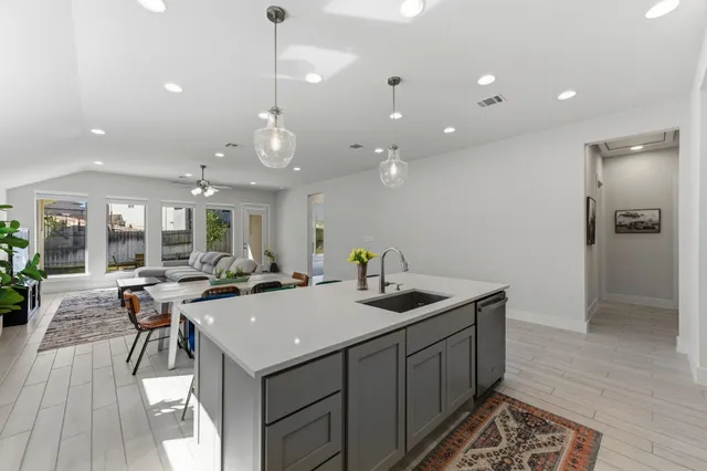 a kitchen with stainless steel appliances granite countertop a refrigerator oven a sink a dining table and chairs with wooden floor