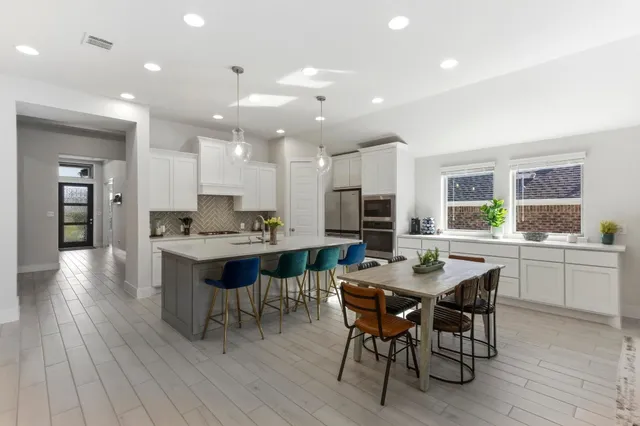 a kitchen with a dining table chairs and wooden floor