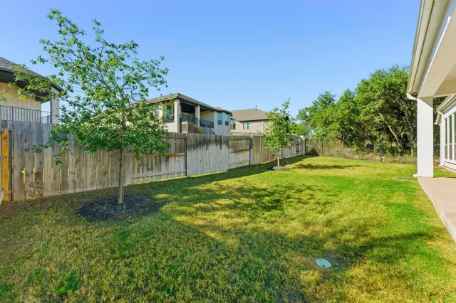 a view of a house with a big yard potted plants and large trees