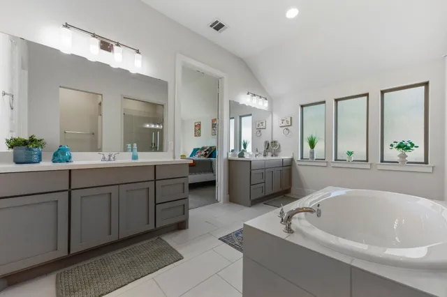 a bathroom with a tub a sink and mirror