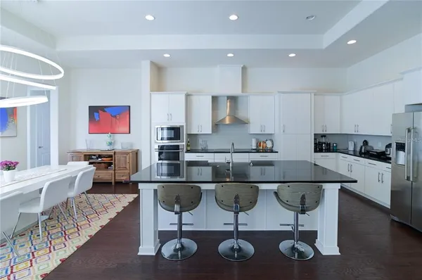 a view of a dining room with furniture one side kitchen view and wooden floor