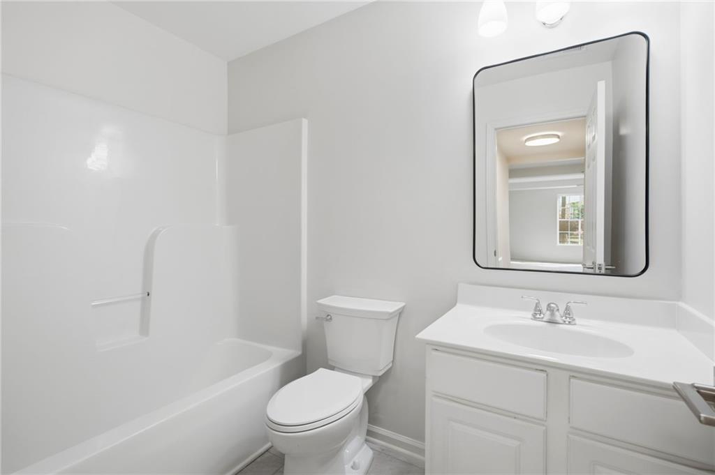 9485 Waldrip Road Gainesville, GA 30506 - Photo 22 of 30 a bathroom with a toilet a sink a mirror a bathtub and vanity