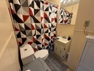 a white toilet sitting next to a bathroom sink and a mirror