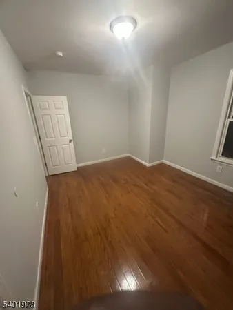 en empty room with wooden floor and fan