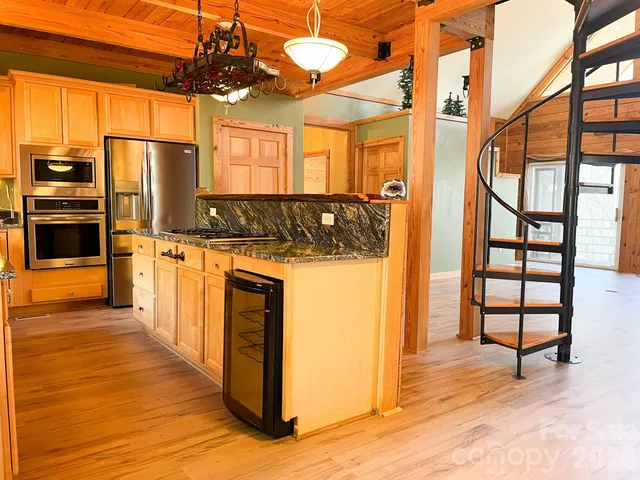 a kitchen with stainless steel appliances granite countertop a refrigerator a stove and a sink with cabinets