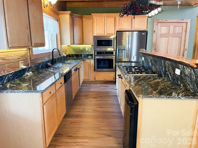 a kitchen with stainless steel appliances granite countertop a stove a sink and a refrigerator