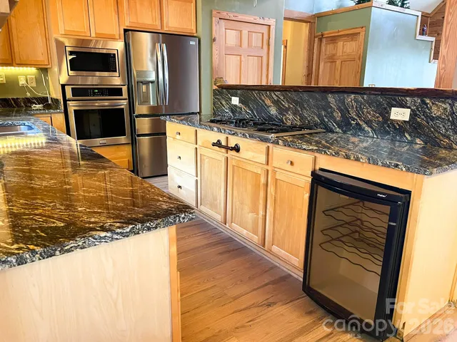 a kitchen with stainless steel appliances kitchen island granite countertop a refrigerator stove and oven