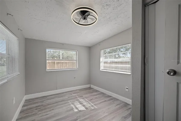 a view of an empty room with window and wooden floor