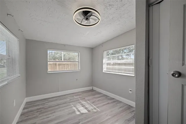 a view of an empty room with window and wooden floor