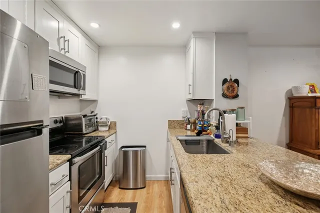 a kitchen with granite countertop a sink stove and refrigerator