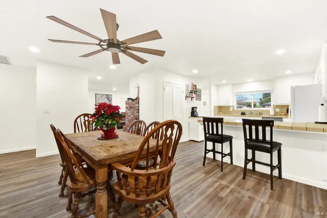 a kitchen with stainless steel appliances a dining table chairs and wooden floor