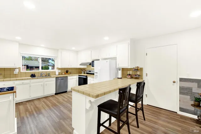a kitchen with a sink a refrigerator and white cabinets
