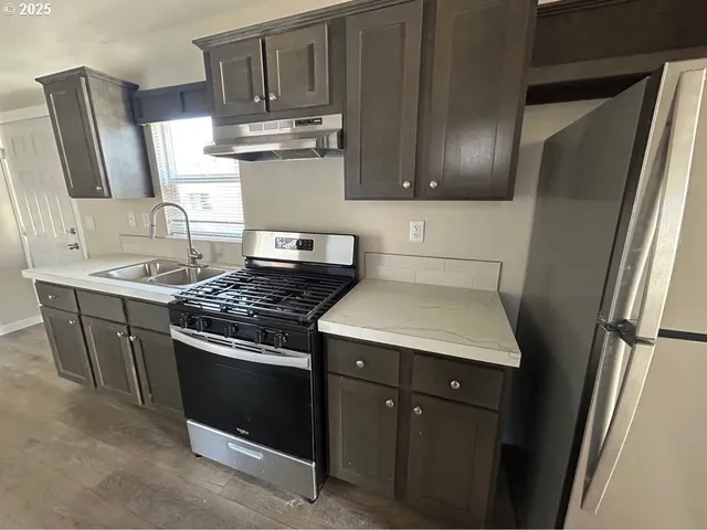 a kitchen with stainless steel appliances granite countertop a stove a refrigerator and a sink