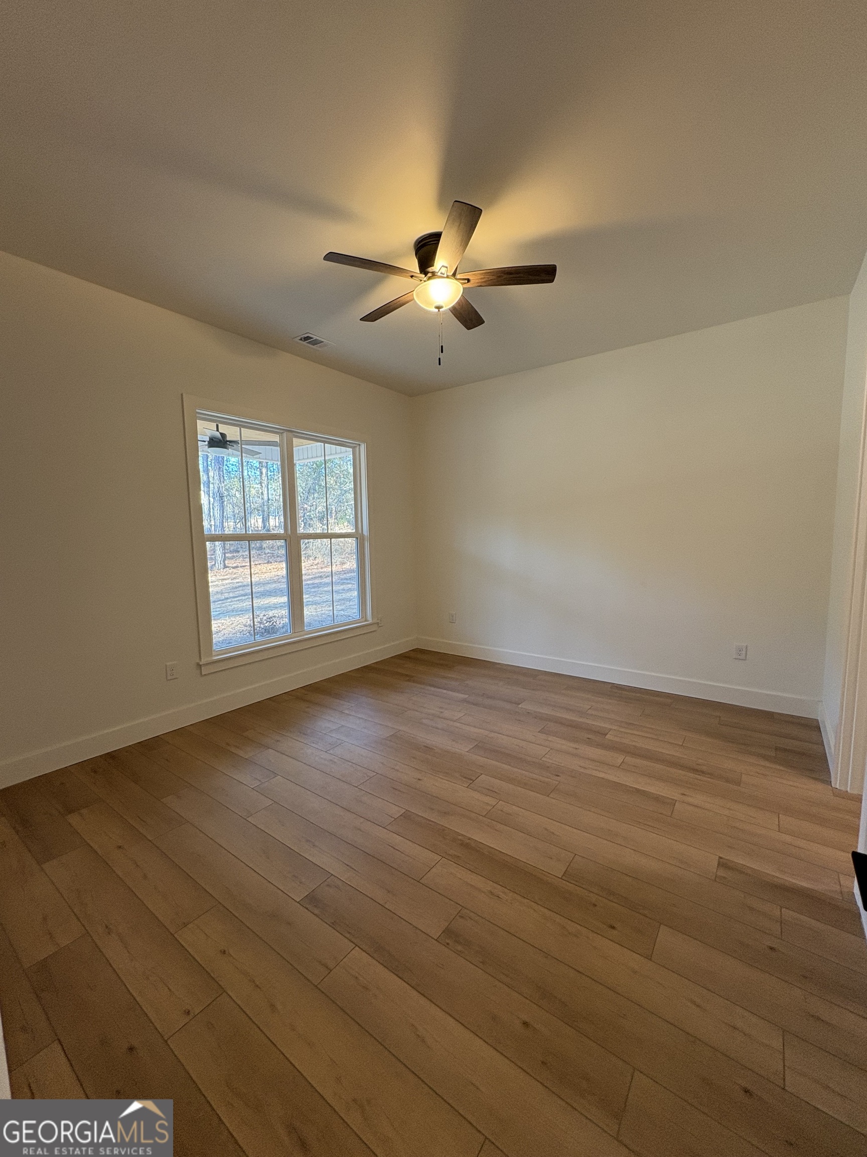 435 Muskogee Trail Dublin, GA 31021 - Photo 12 of 31 an empty room with wooden floor ceiling fan and windows