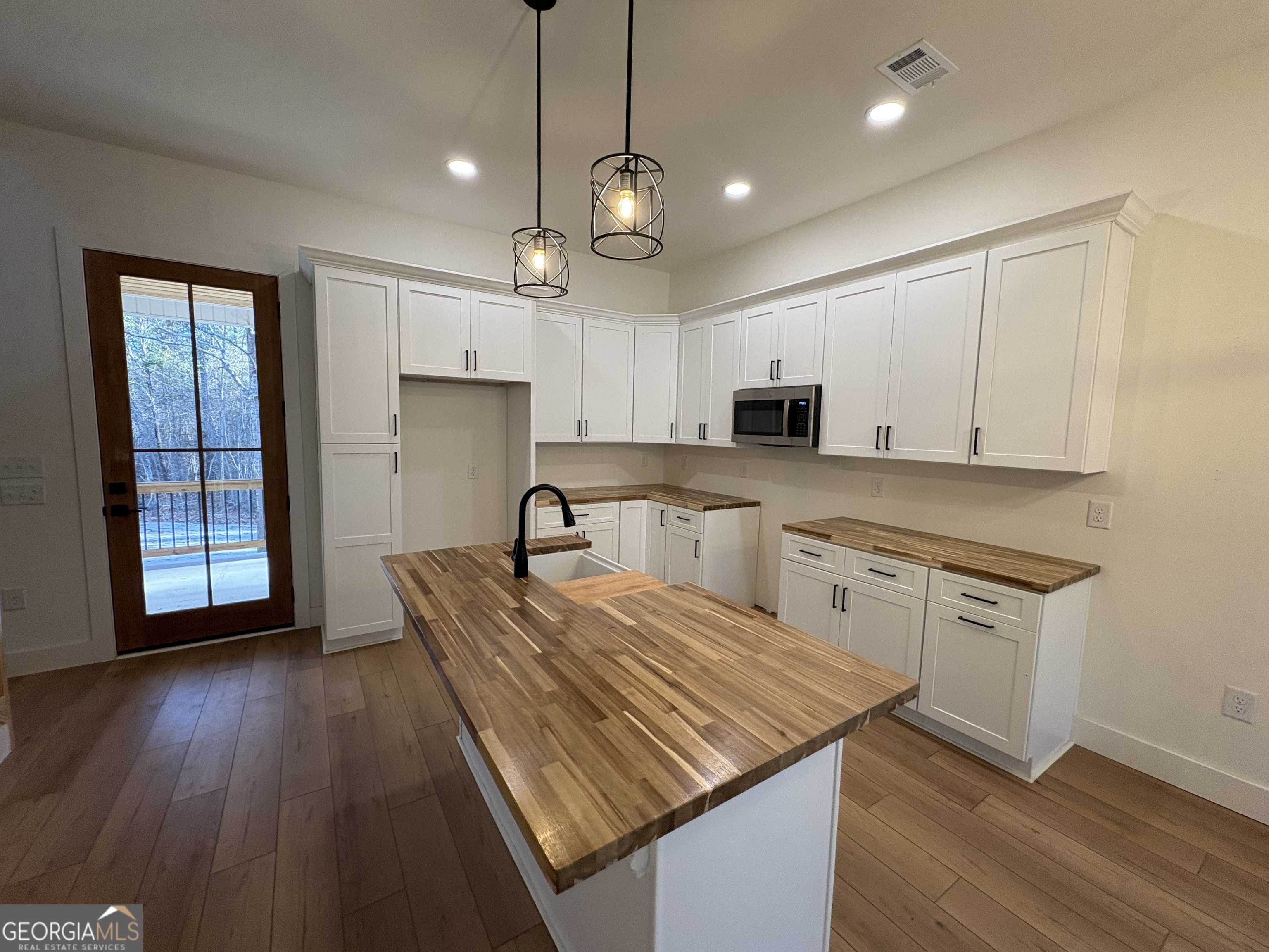 435 Muskogee Trail Dublin, GA 31021 - Photo 8 of 31 a kitchen with granite countertop wooden floors a center island stainless steel appliances and cabinets