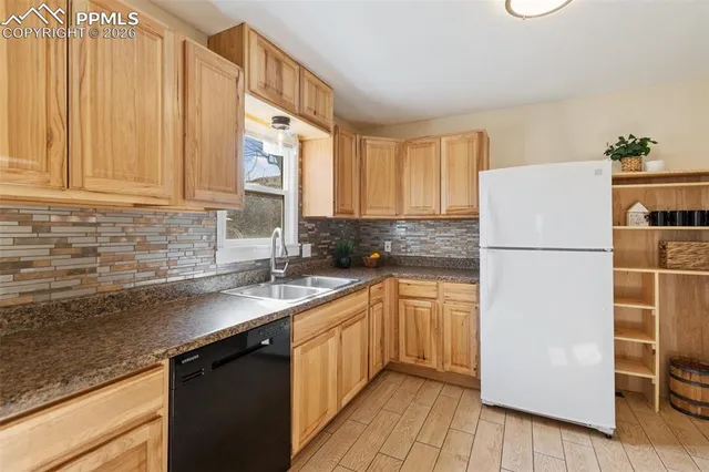 a kitchen with a refrigerator a sink and dishwasher with wooden cabinets