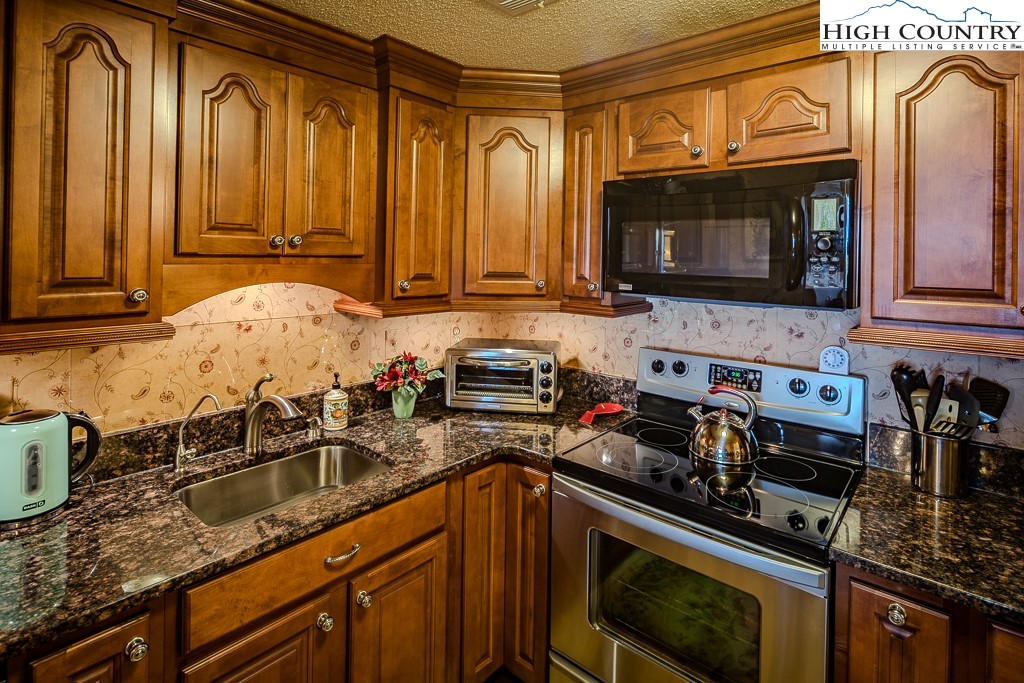 303 Sugar Top Drive, Unit 43427 Sugar Mountain, NC 28604 - Photo 10 of 18 a kitchen with granite countertop a sink a stove and cabinets