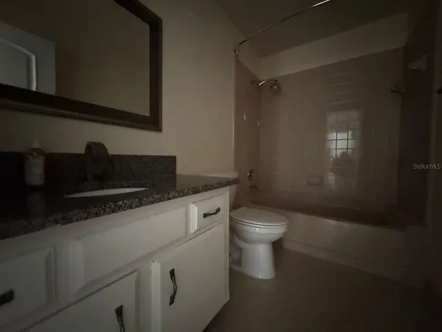 a bathroom with a granite countertop sink a toilet and with shower