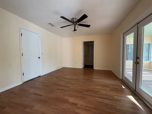 a view of empty room with wooden floor and fan