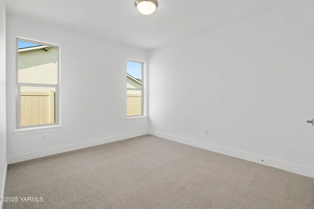 a view of an empty room with kitchen and a window