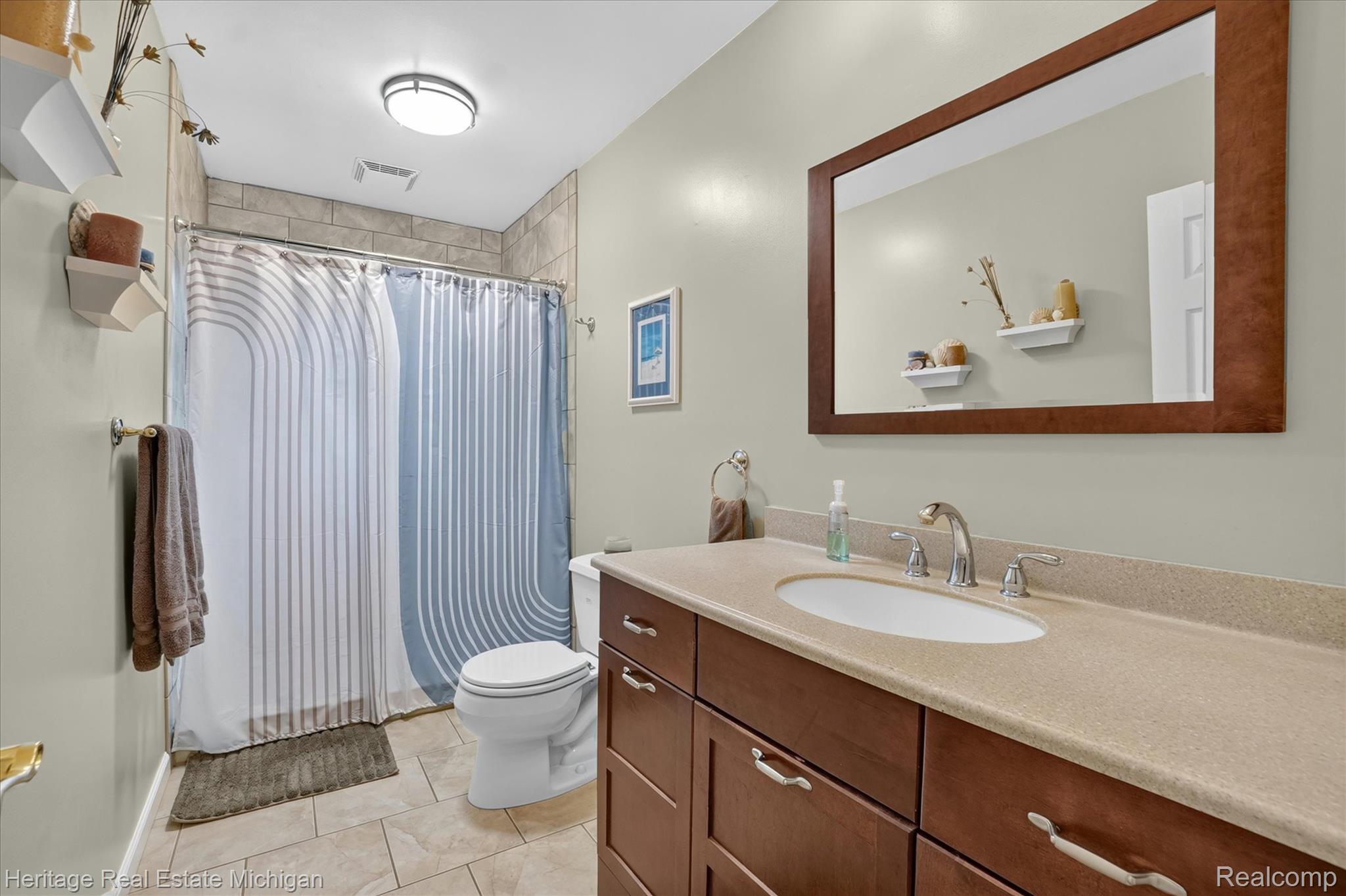 14038 North Hogan Road Linden, MI 48451 - Photo 26 of 53 Bathroom featuring a vanity with a light-colored countertop, an undermount sink, and a dark wood-finish cabinet