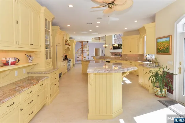 a view of a kitchen with kitchen island stainless steel appliances a stove a sink a refrigerator and a fireplace