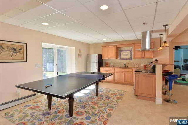 a living room with stainless steel appliances furniture a rug kitchen view and a table
