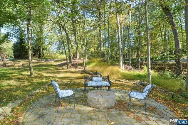 a view of swimming pool with lawn chairs and large trees