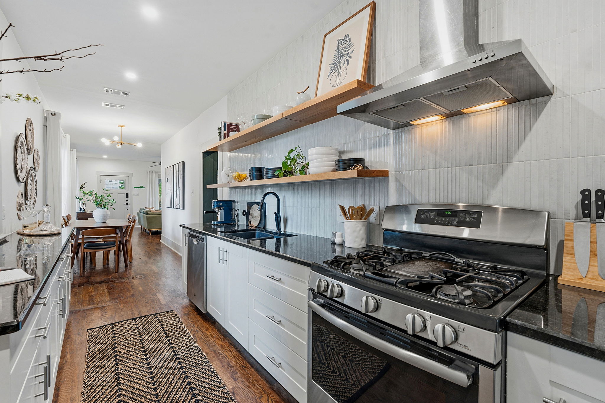 1122 Gunter Street Austin, TX 78702 - Photo 12 of 23 The kitchen features a stainless steel range with a ventilation hood, open shelving, and dark countertops