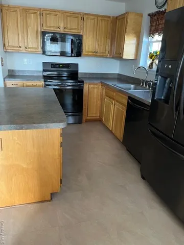 a kitchen with granite countertop a sink stove and microwave