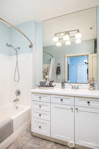 a bathroom with a sink vanity granite tub shower and a mirror
