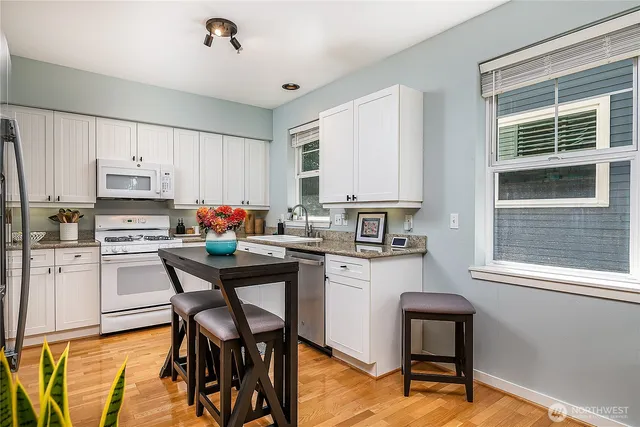 a kitchen with stainless steel appliances kitchen island granite countertop a table chairs sink and cabinets