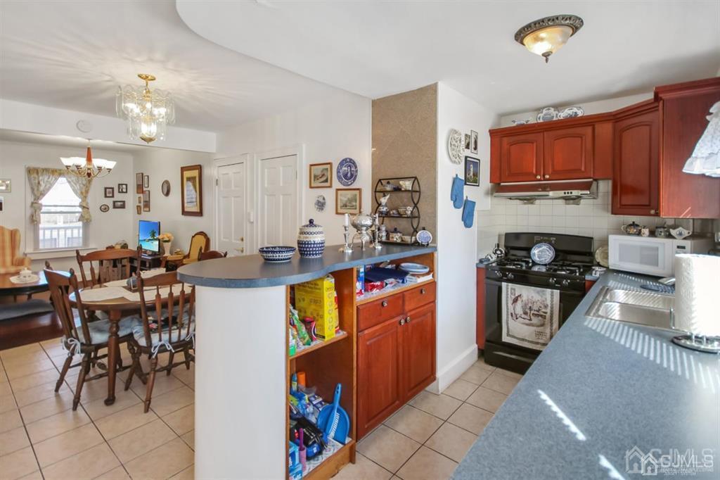 122 South Lincoln Avenue Middlesex, NJ 08846 - Photo 10 of 37 a kitchen with stainless steel appliances granite countertop a stove top oven a sink a dining table and chairs with the living room view