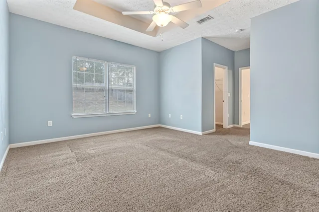 an empty room with windows and chandelier fan