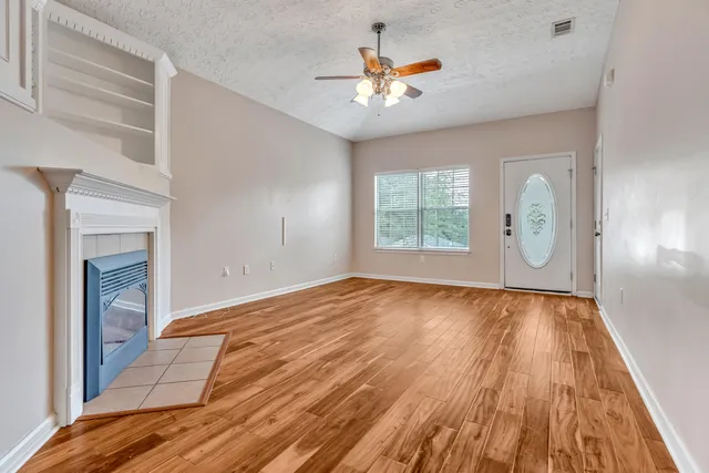a view of an empty room with window and wooden floor