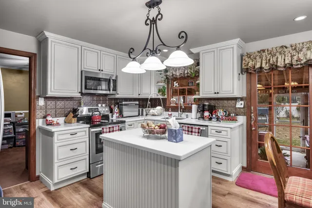 a kitchen with kitchen island granite countertop a sink a counter space appliances and cabinets