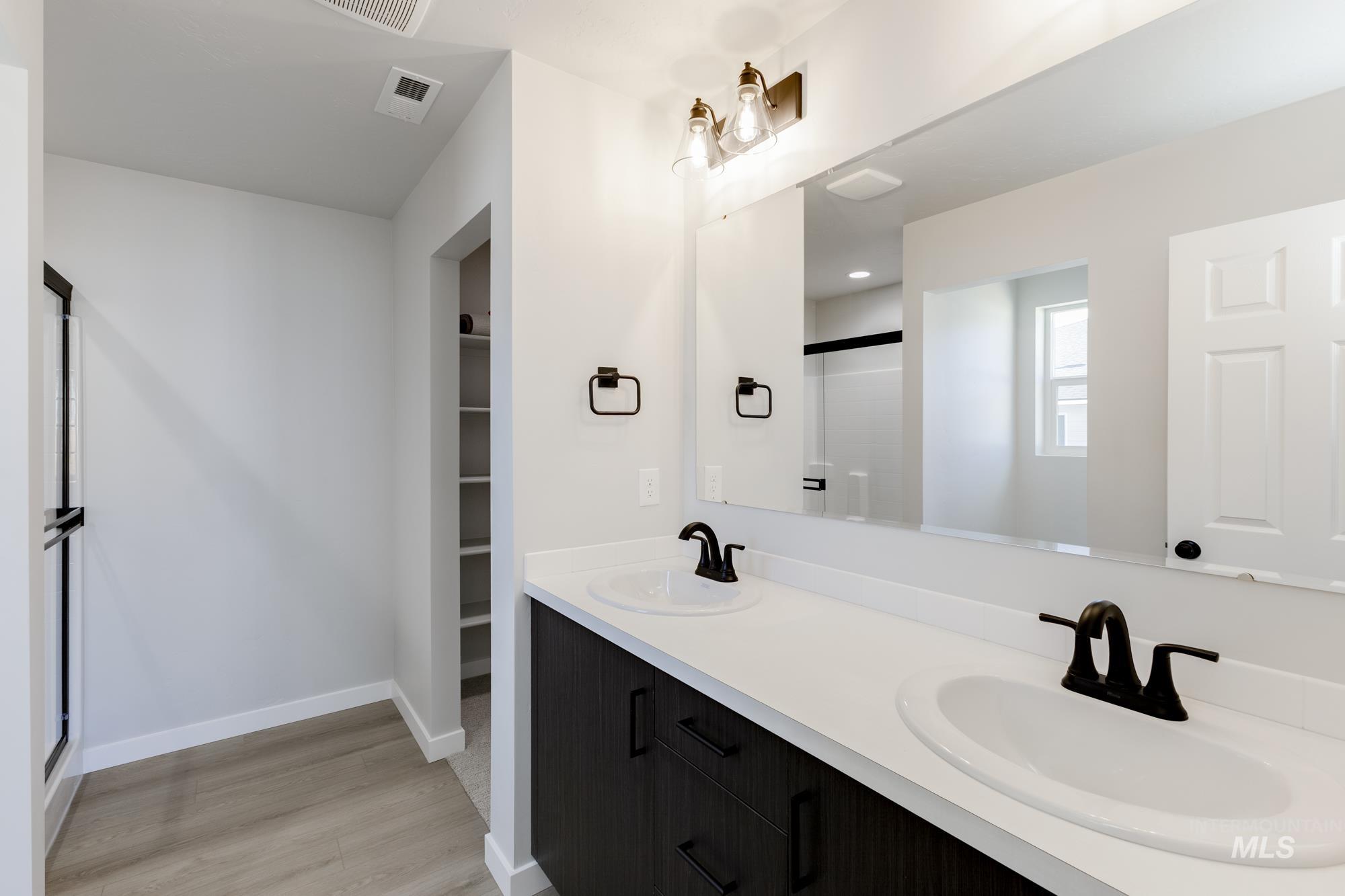 1804 West Unforgettable Street Meridian, ID 83642 - Photo 16 of 18 Bathroom featuring a stall shower, double vanity, a walk in closet, and light wood finished floors
