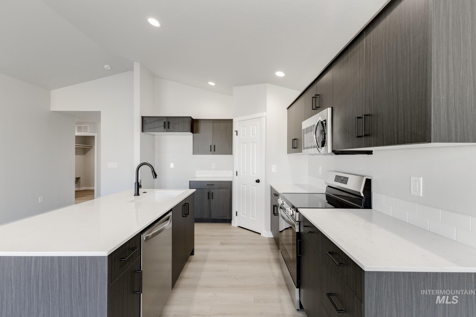 1804 West Unforgettable Street Meridian, ID 83642 - Photo 5 of 18 Kitchen with stainless steel appliances, light stone countertops, a kitchen island with sink, light wood finished floors, and modern cabinets