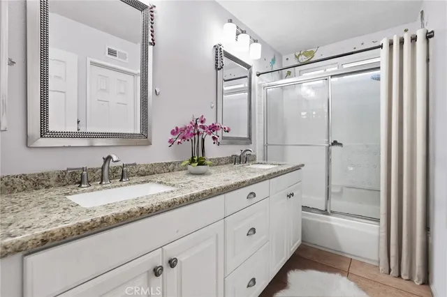a bathroom with a granite countertop sink mirror shower and double