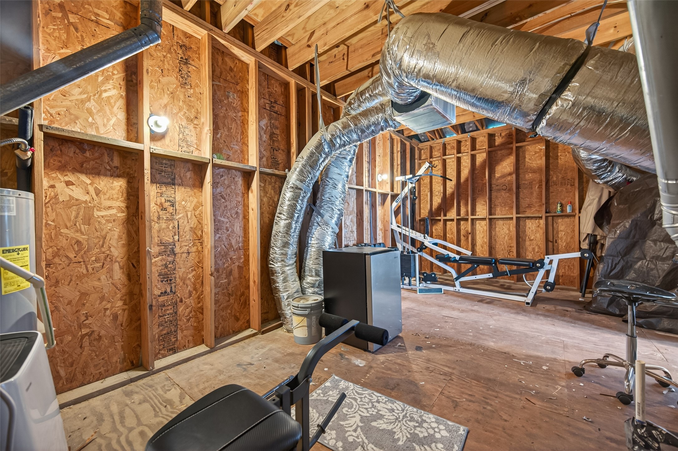 2611 Riverside Drive, Unit C Houston, TX 77004 - Photo 47 of 50 This photo showcases an unfinished attic space equipped with fitness equipment. The area features exposed wooden framing and ductwork, providing a functional space for home workouts or potential for further customization.