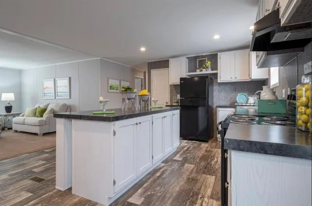 a kitchen with stainless steel appliances granite countertop a table chairs sink refrigerator and cabinets