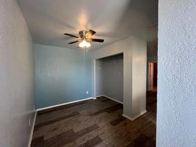 an empty room with wooden floor and a chandelier fan