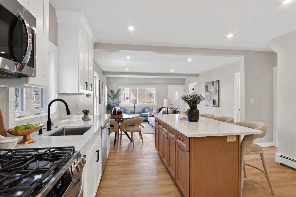 5 Springdale Avenue Saugus, MA 01906 - Photo 5 of 26 a open kitchen with stainless steel appliances granite countertop a stove top oven a sink dishwasher a dining table and chairs with wooden floor