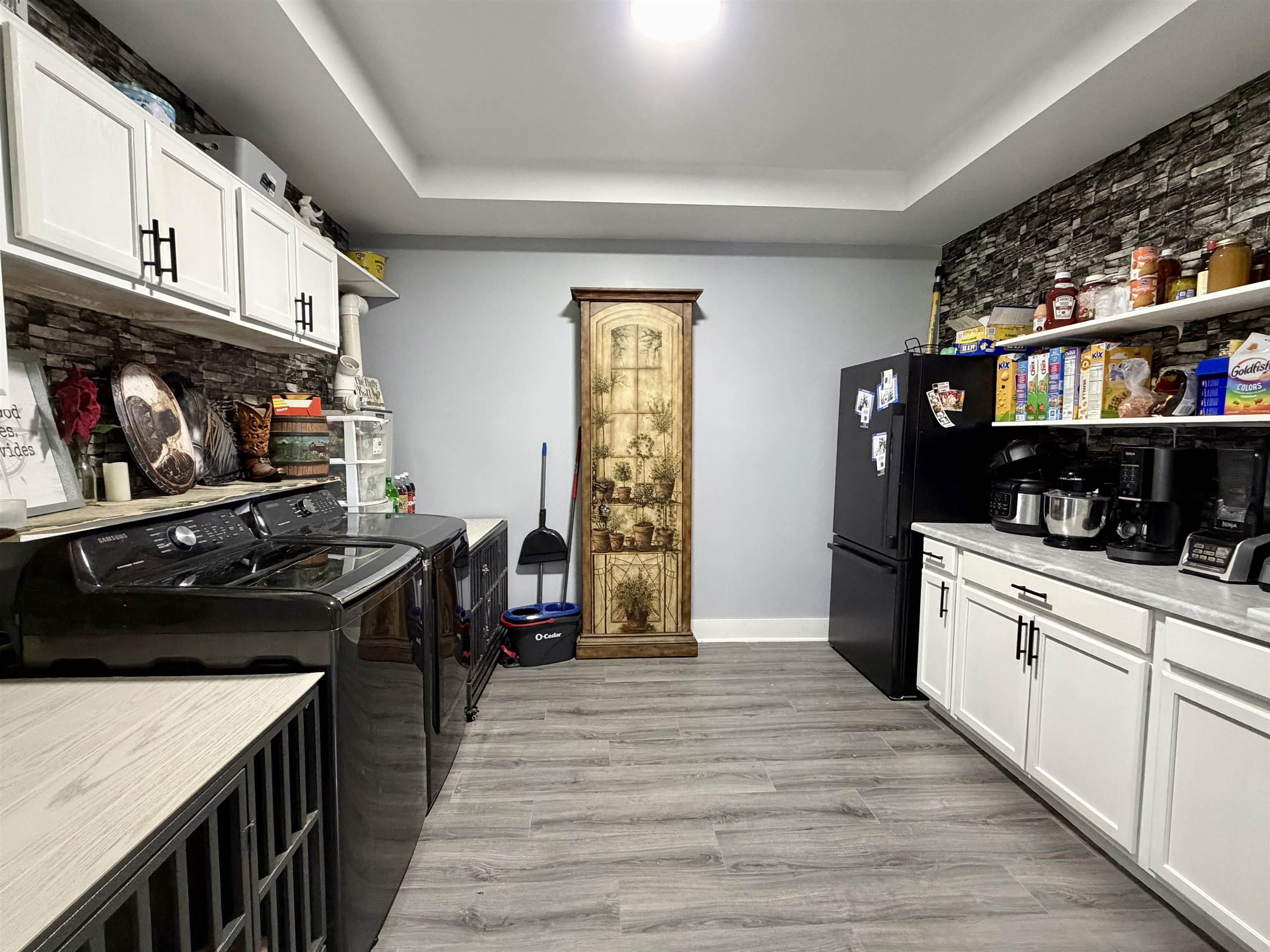 3670 Peavine Road Middleton, TN 38052 - Photo 13 of 36 Laundry and utility area featuring white shaker-style cabinetry, open shelving, and a stone-effect accent wall
