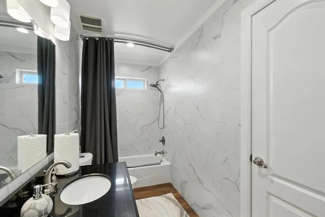 a bathroom with a granite countertop sink toilet and shower