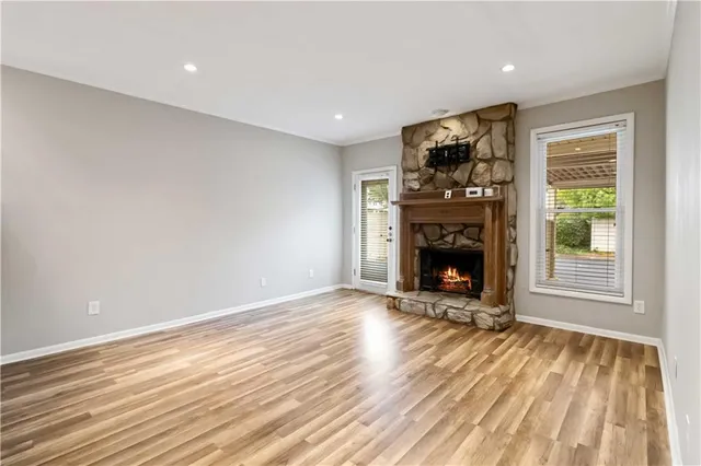a view of an empty room with wooden floor fireplace and a window